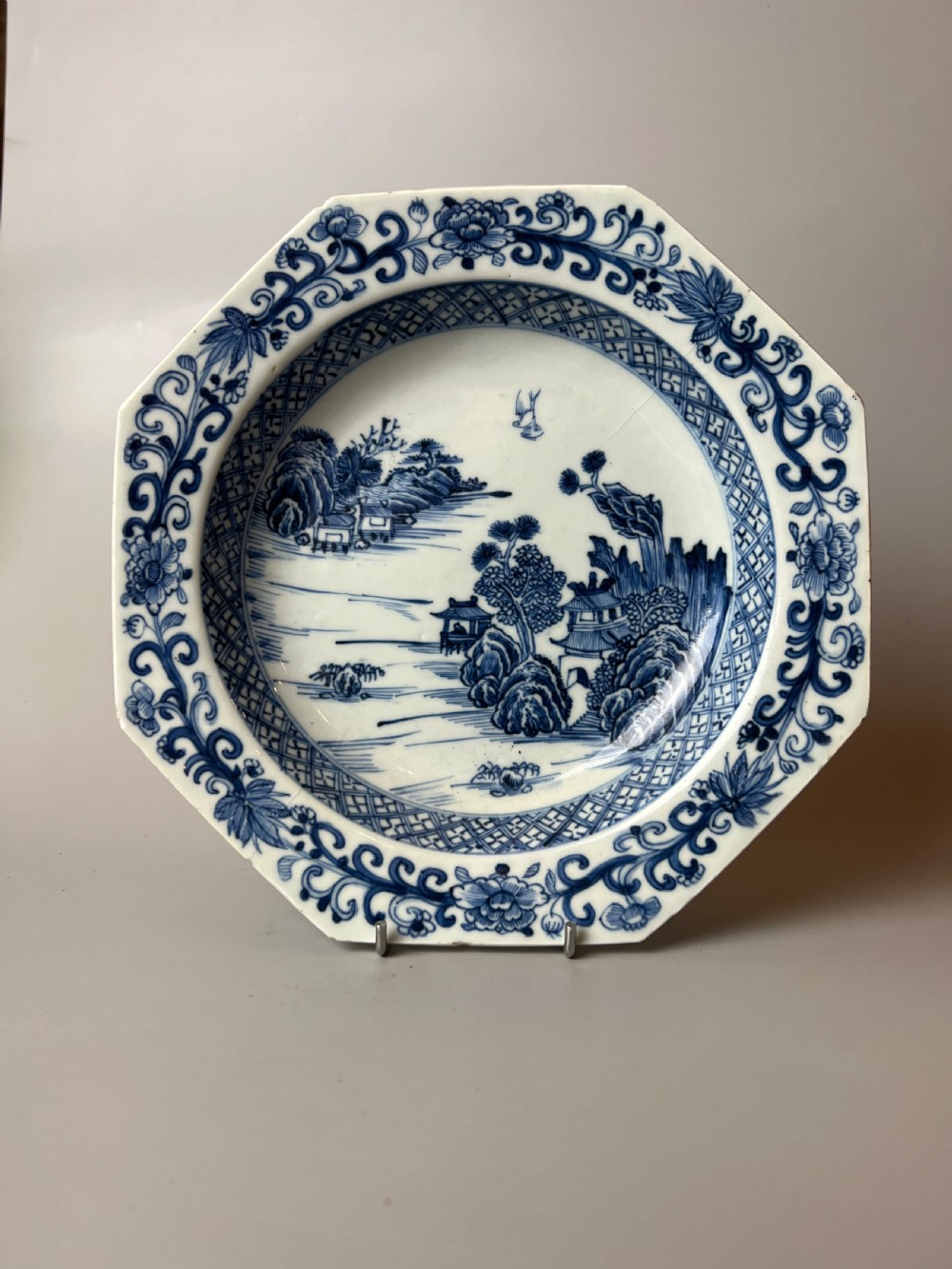 A late 18th-century Chinese export porcelain plate featuring hand-painted cobalt blue river landscapes, pagodas, and a patterned border on a white background.