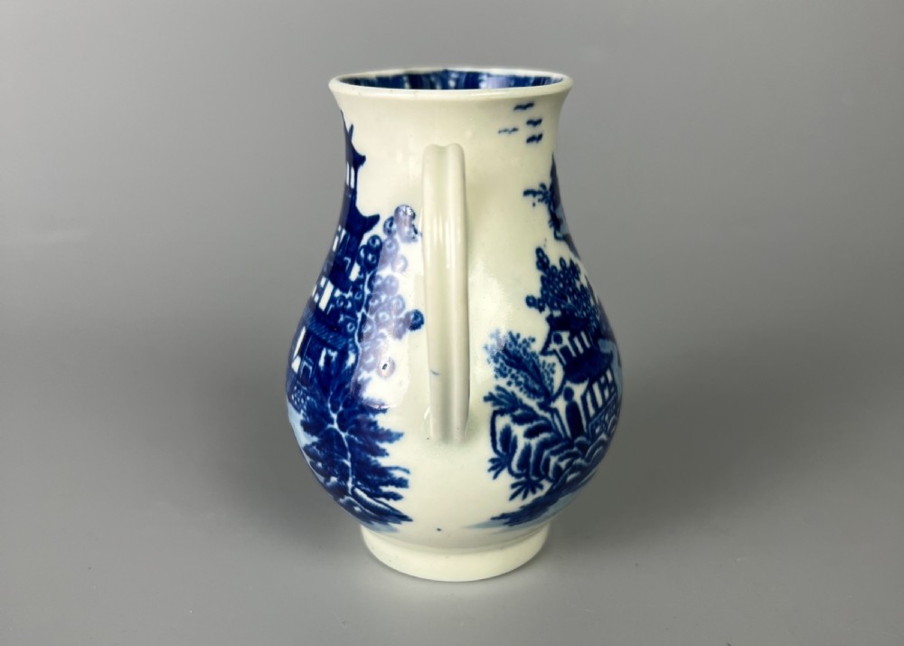 An 18th-century Worcester soft-paste porcelain sparrowbeak jug decorated with a blue and white chinoiserie Bandstand pattern. View IV