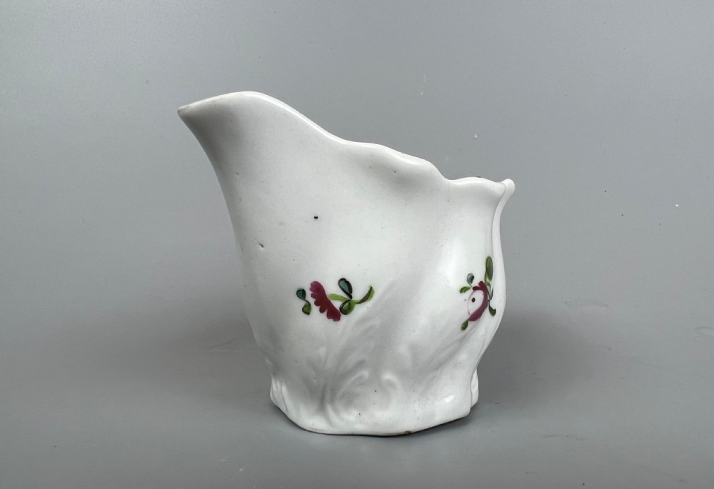 An 18th-century white soft-paste porcelain low Chelsea ewer decorated with hand-painted floral sprigs and leaf moulding. View V