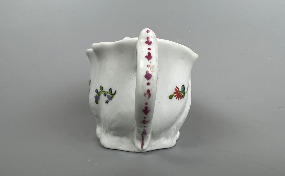 An 18th-century white soft-paste porcelain low Chelsea ewer decorated with hand-painted floral sprigs and leaf moulding. View VI