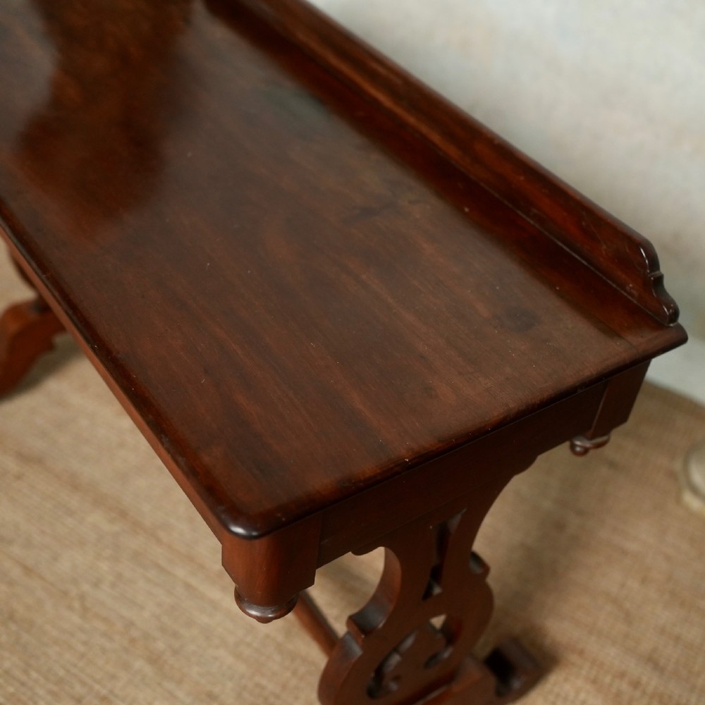 Victorian mahogany writing table with a low rear gallery, turned stretcher, and shaped trestle end supports on castors. View II