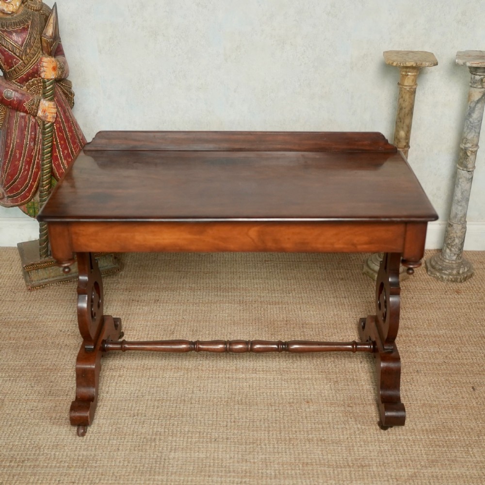 Victorian mahogany writing table with a low rear gallery, turned stretcher, and shaped trestle end supports on castors. View IV
