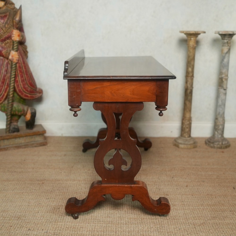Victorian mahogany writing table with a low rear gallery, turned stretcher, and shaped trestle end supports on castors. View VIII