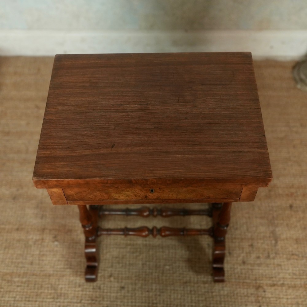 A nineteenth-century rosewood games table featuring a swivel folding top with inlaid chess and backgammon boards, resting on turned trestle supports with a fabric sewing basket underneath. View VII