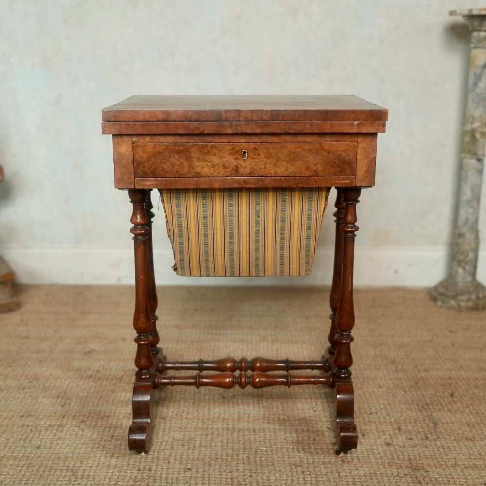 A nineteenth-century rosewood games table featuring a swivel folding top with inlaid chess and backgammon boards, resting on turned trestle supports with a fabric sewing basket underneath. View VIII