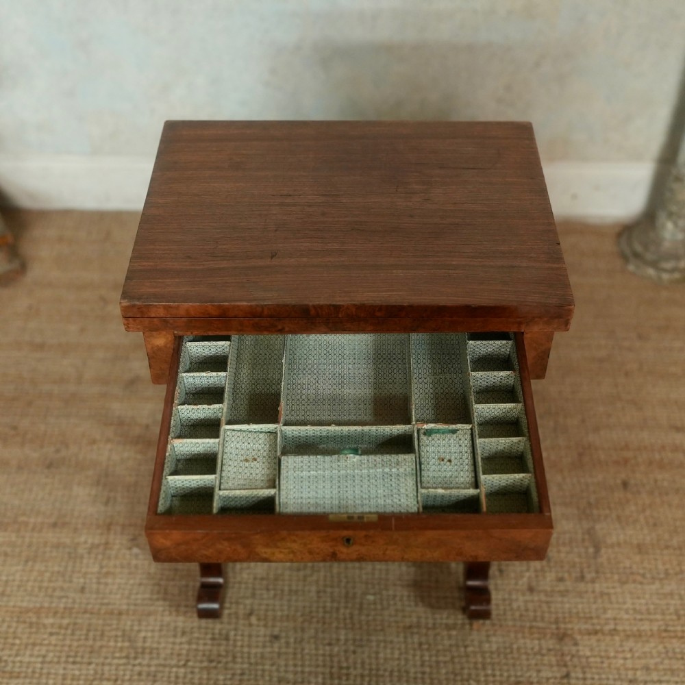 A nineteenth-century rosewood games table featuring a swivel folding top with inlaid chess and backgammon boards, resting on turned trestle supports with a fabric sewing basket underneath. View XI