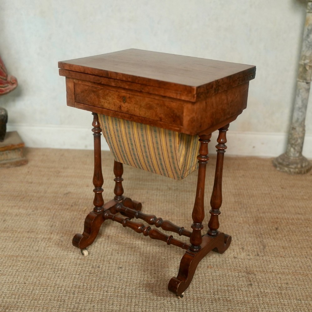 A nineteenth-century rosewood games table featuring a swivel folding top with inlaid chess and backgammon boards, resting on turned trestle supports with a fabric sewing basket underneath. View XII