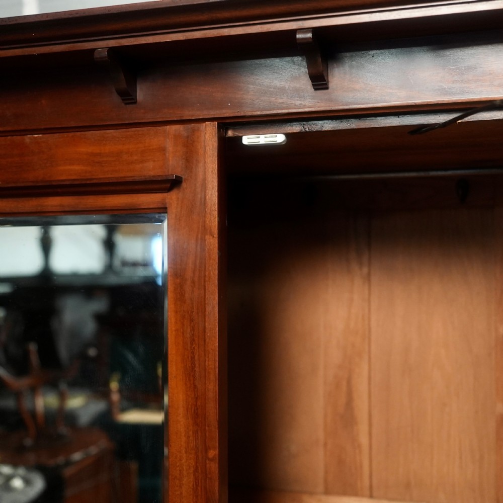 An Edwardian mahogany wardrobe featuring a central full-length mirror door flanked by inlaid timber doors over two lower drawers. View VII