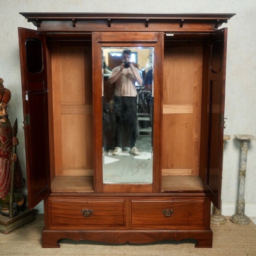 An Edwardian mahogany wardrobe featuring a central full-length mirror door flanked by inlaid timber doors over two lower drawers. View II