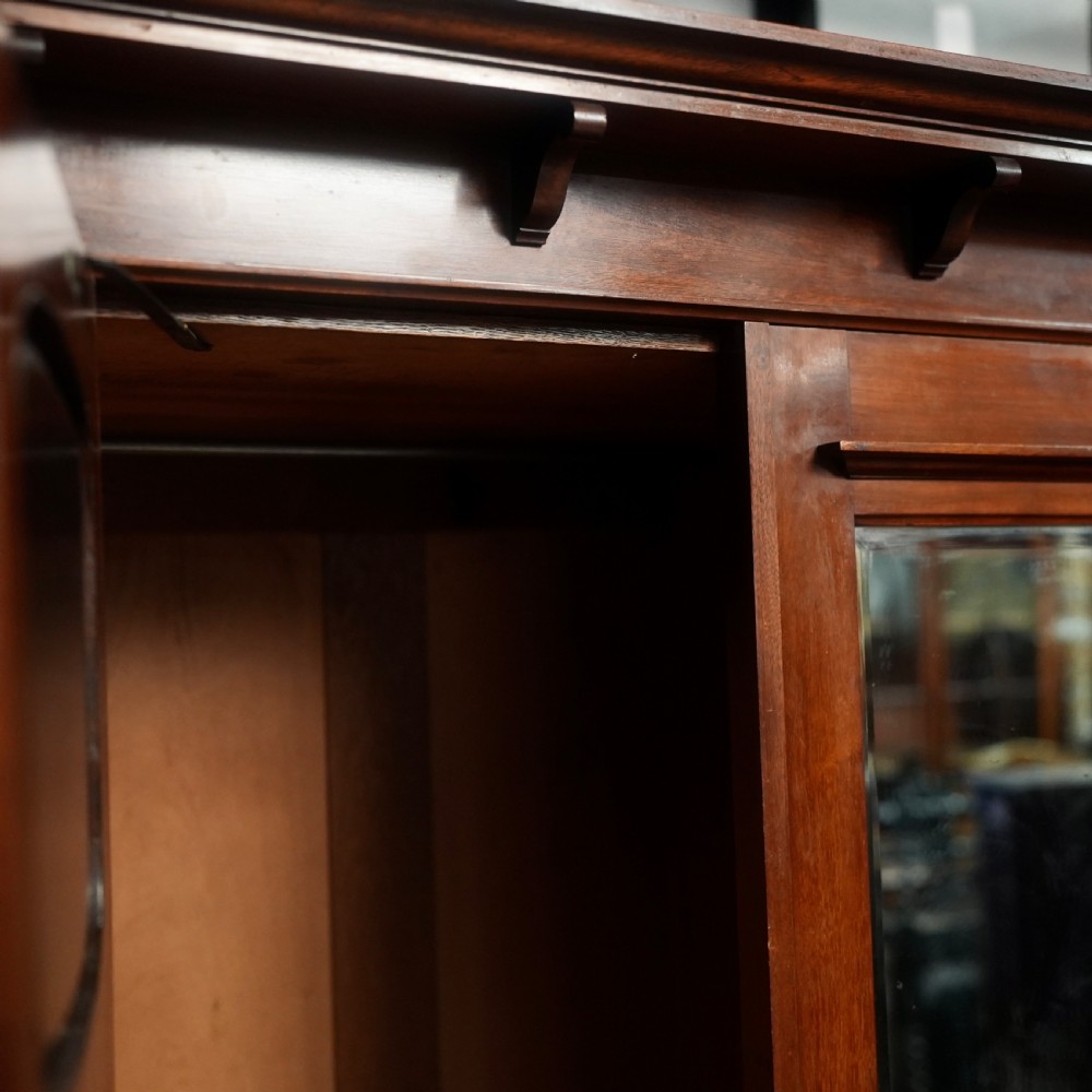 An Edwardian mahogany wardrobe featuring a central full-length mirror door flanked by inlaid timber doors over two lower drawers. View III