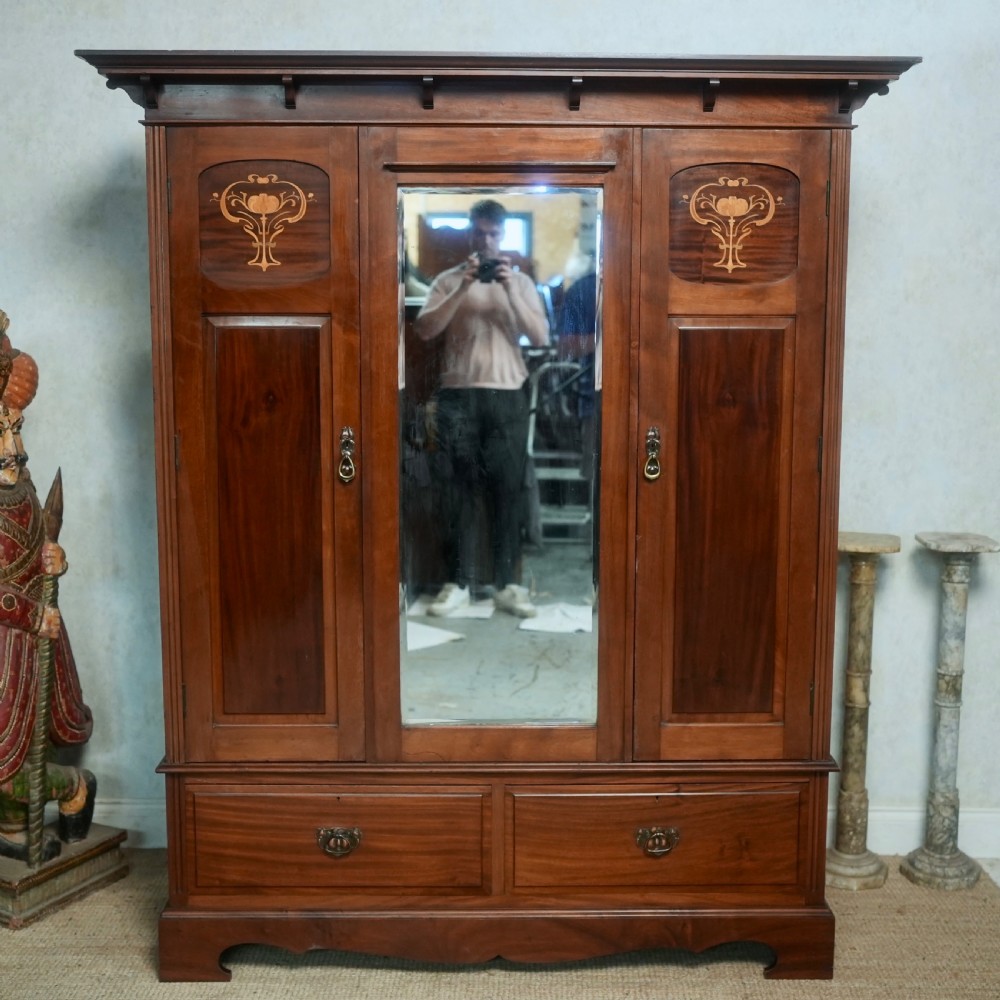 An Edwardian mahogany wardrobe featuring a central full-length mirror door flanked by inlaid timber doors over two lower drawers. View IV