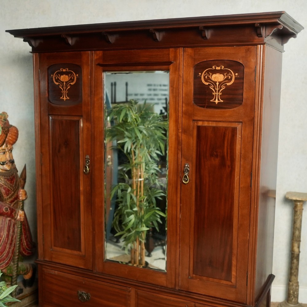 An Edwardian mahogany wardrobe featuring a central full-length mirror door flanked by inlaid timber doors over two lower drawers. View V