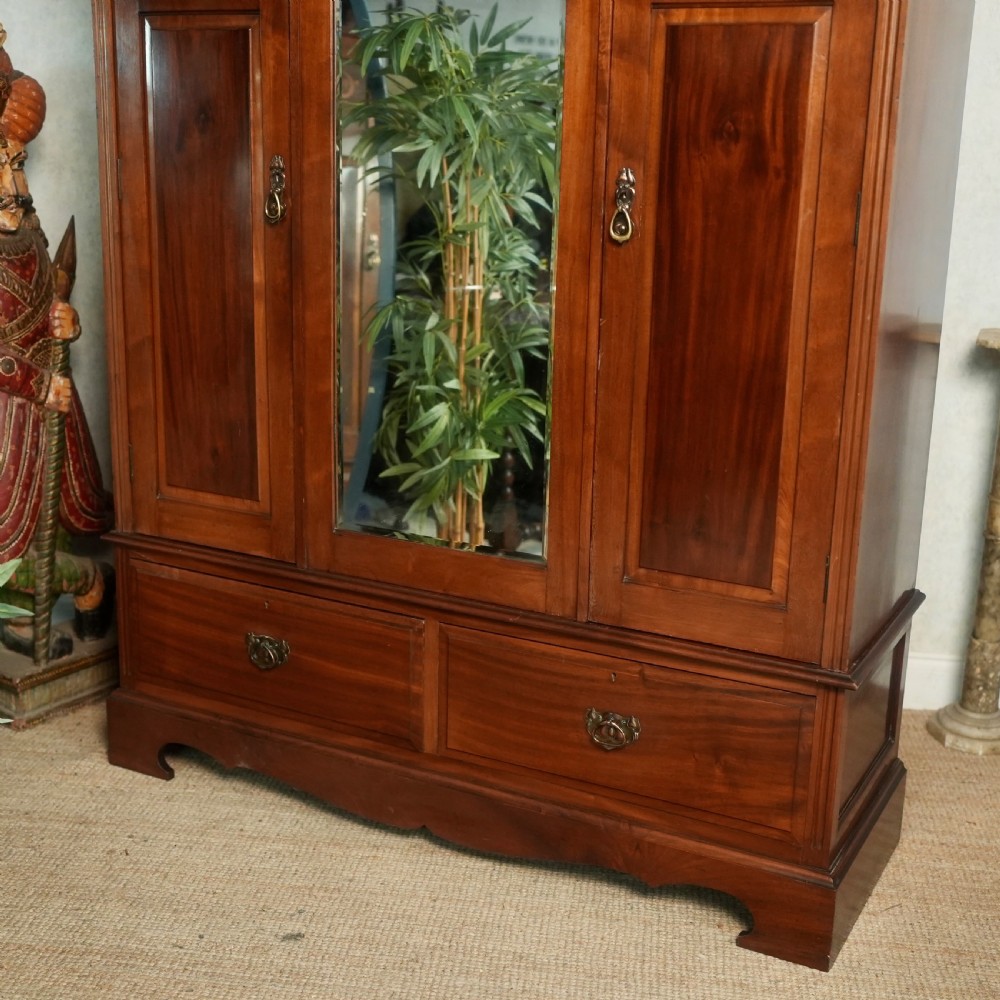An Edwardian mahogany wardrobe featuring a central full-length mirror door flanked by inlaid timber doors over two lower drawers. View VI