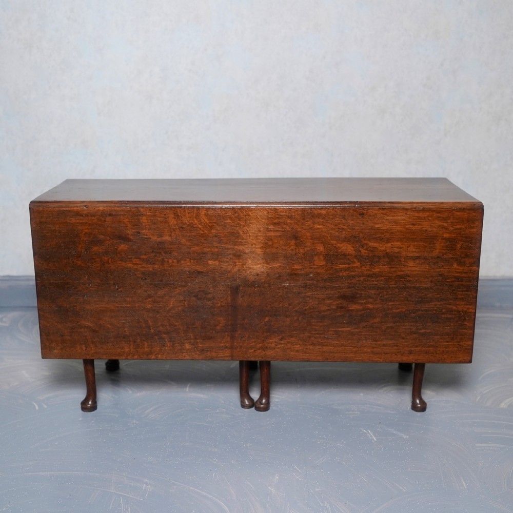An 18th-century oak gateleg dining table featuring drop-leaf flaps supported by swinging legs terminating in pad feet. View IV