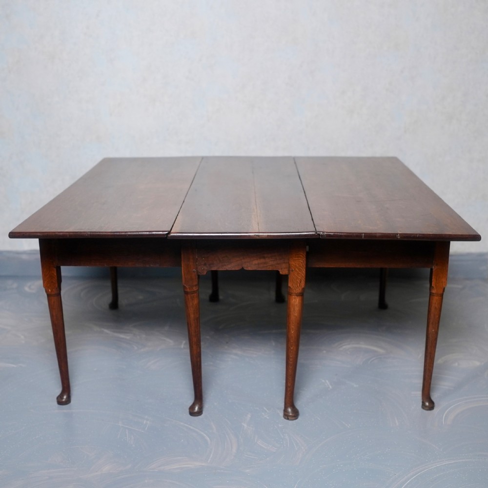 An 18th-century oak gateleg dining table featuring drop-leaf flaps supported by swinging legs terminating in pad feet.