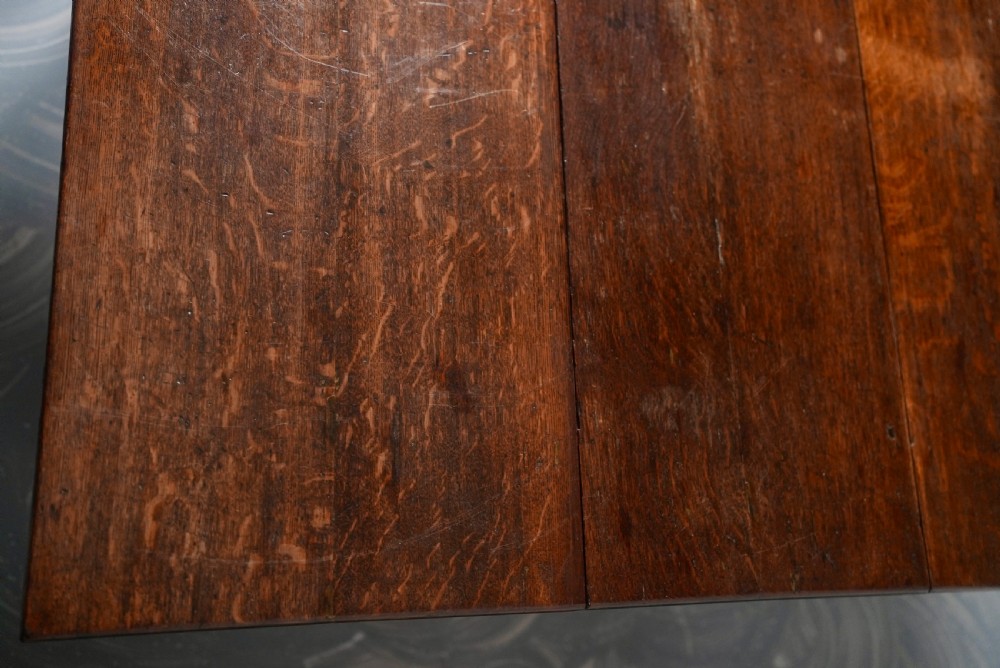 An 18th-century oak gateleg dining table featuring drop-leaf flaps supported by swinging legs terminating in pad feet. View V