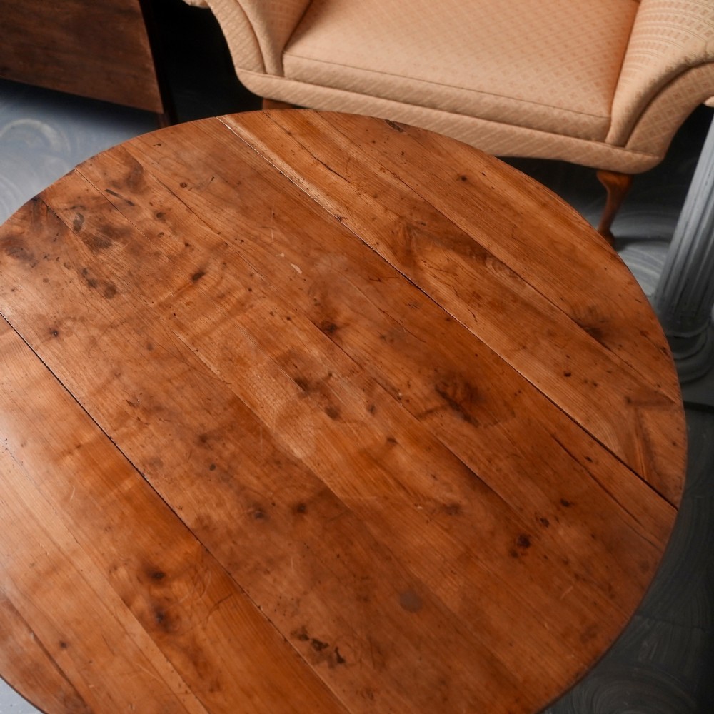 An antique French fruitwood drop-leaf dining table with turned legs, castors, and a warm honey-toned wood grain. View IX