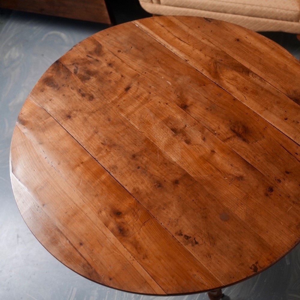 An antique French fruitwood drop-leaf dining table with turned legs, castors, and a warm honey-toned wood grain. View X