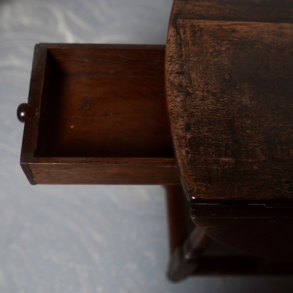An eighteenth-century dark oak gateleg table shown with drop-leaf sides folded down, featuring turned legs and lower stretchers. View III