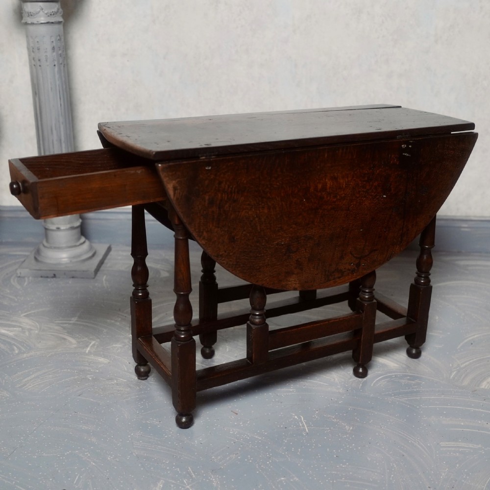 An eighteenth-century dark oak gateleg table shown with drop-leaf sides folded down, featuring turned legs and lower stretchers. View IV