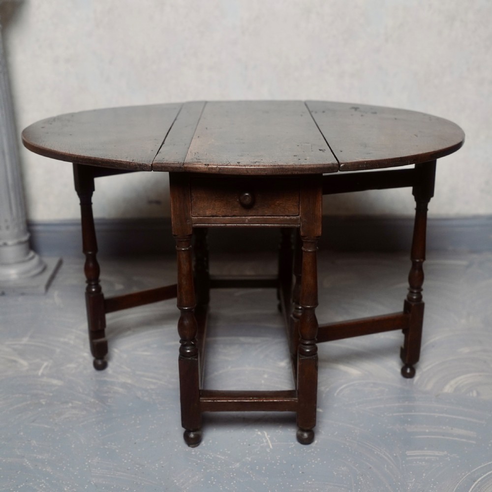 An eighteenth-century dark oak gateleg table shown with drop-leaf sides folded down, featuring turned legs and lower stretchers. View VIII