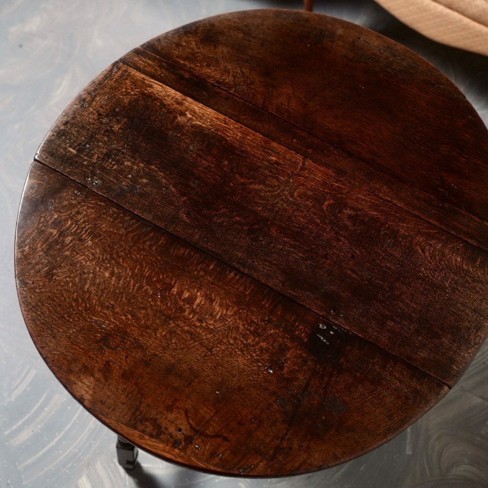 An eighteenth-century dark oak gateleg table shown with drop-leaf sides folded down, featuring turned legs and lower stretchers. View X