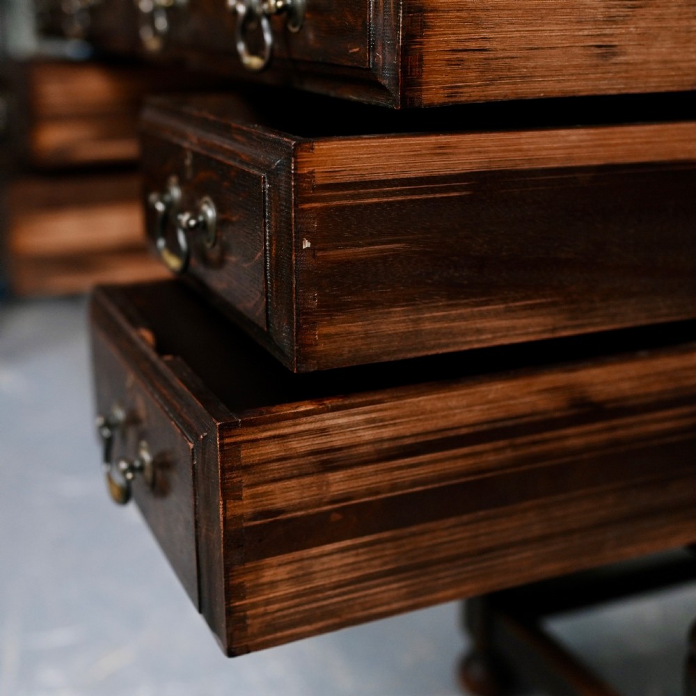 An antique dark oak kneehole desk featuring a leather-inset writing surface, six drawers with brass handles, and turned legs connected by stretchers. View IX