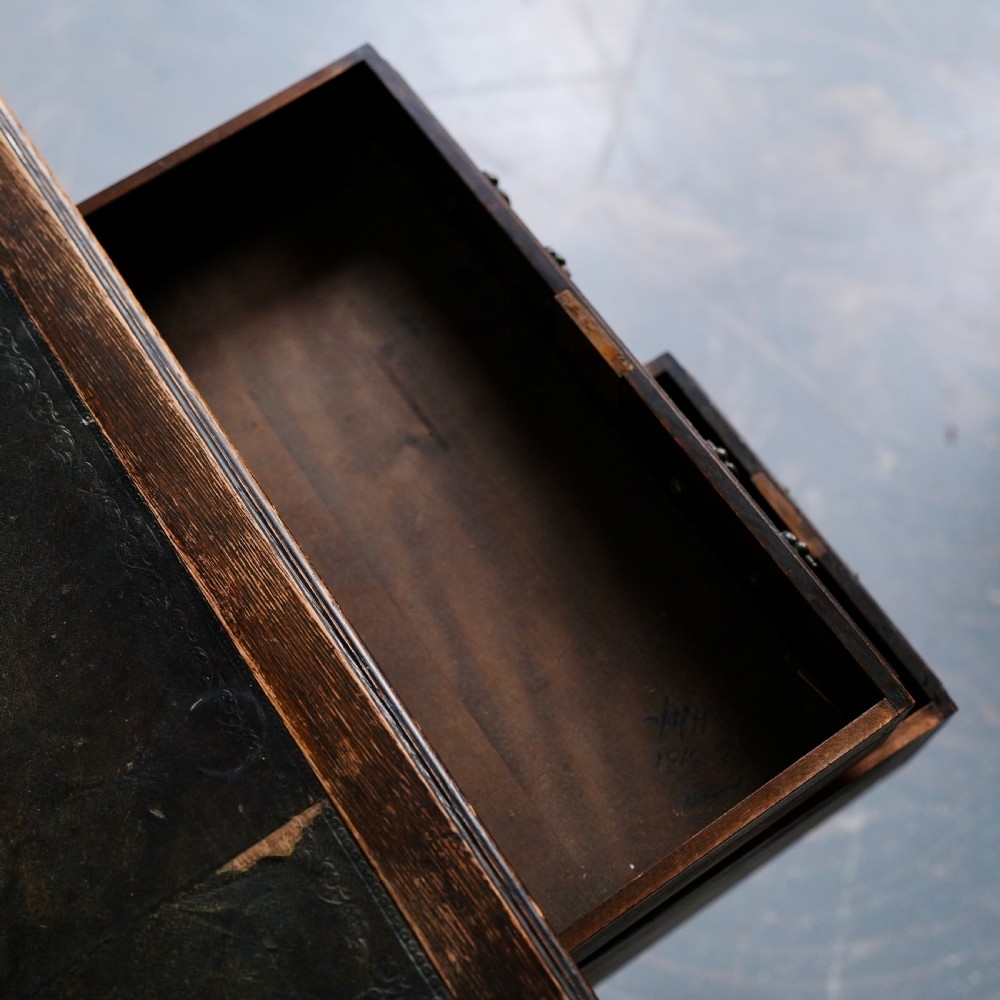 An antique dark oak kneehole desk featuring a leather-inset writing surface, six drawers with brass handles, and turned legs connected by stretchers. View X