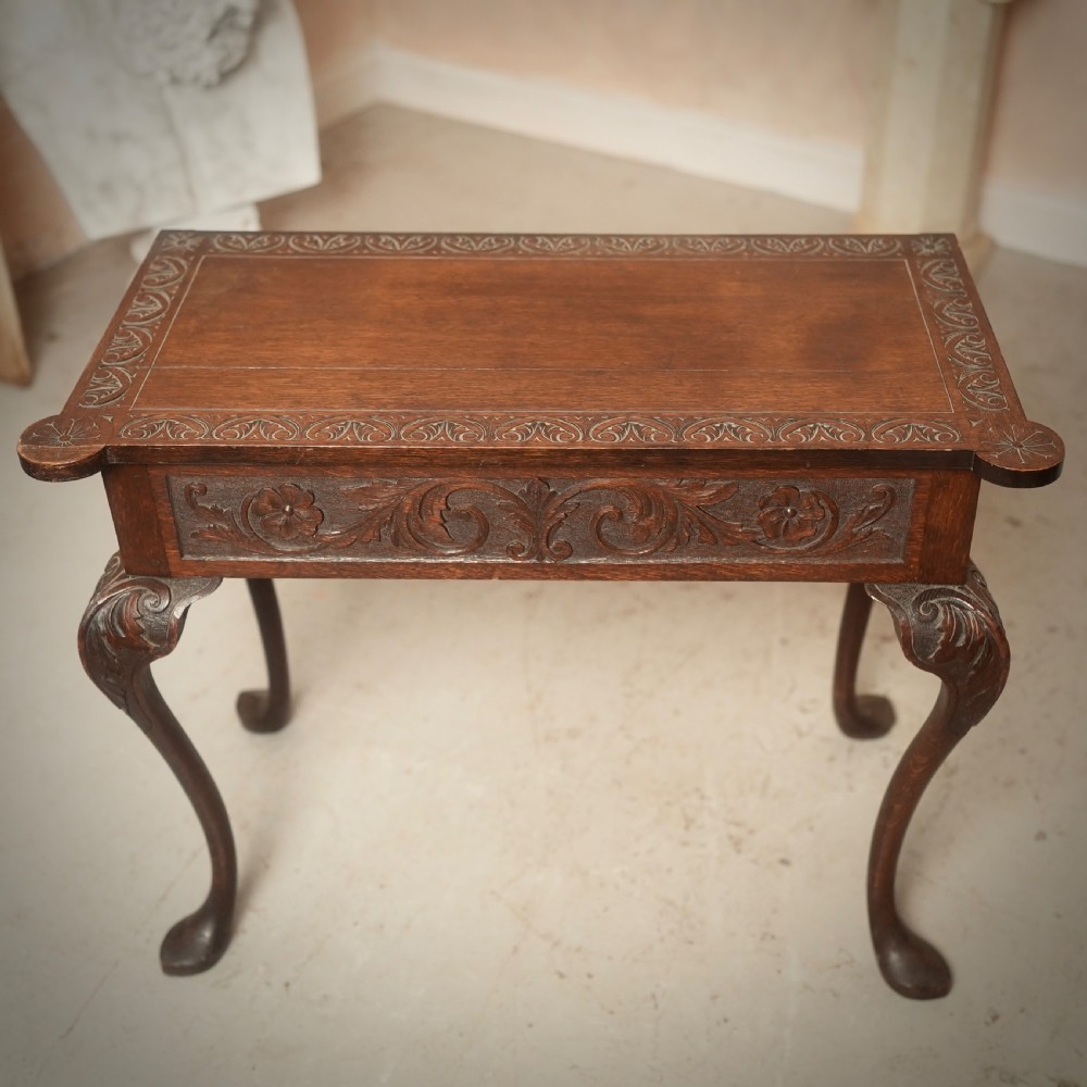 An 18th-century Irish dark oak writing table featuring a hand-carved floral apron and slender cabriole legs. View II