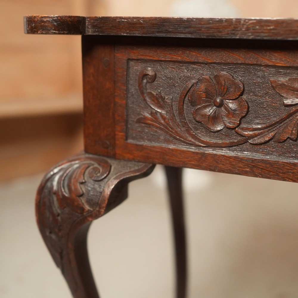 An 18th-century Irish dark oak writing table featuring a hand-carved floral apron and slender cabriole legs. View V