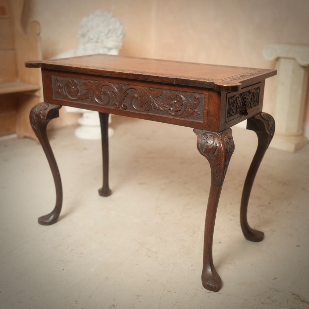 An 18th-century Irish dark oak writing table featuring a hand-carved floral apron and slender cabriole legs. View VII