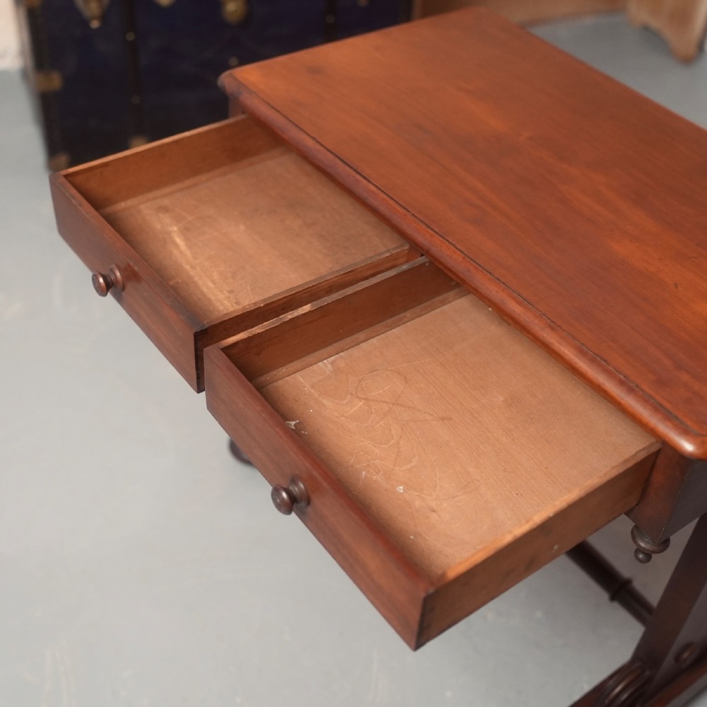 A 19th-century mahogany writing table with two drawer fronts, turned wooden knobs, corner pendants, and a turned central stretcher between trestle legs. View V