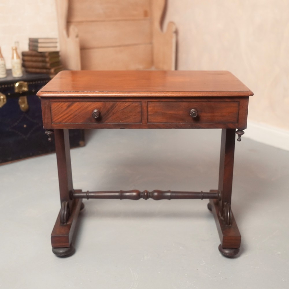 A 19th-century mahogany writing table with two drawer fronts, turned wooden knobs, corner pendants, and a turned central stretcher between trestle legs. View VII