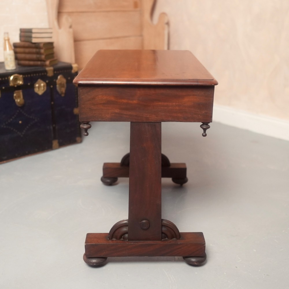 A 19th-century mahogany writing table with two drawer fronts, turned wooden knobs, corner pendants, and a turned central stretcher between trestle legs. View VIII