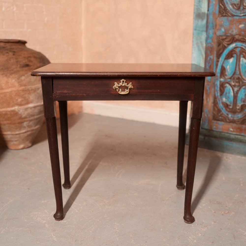 An 18th-century dark mahogany writing table featuring a single drawer with a brass handle plate and slender legs.