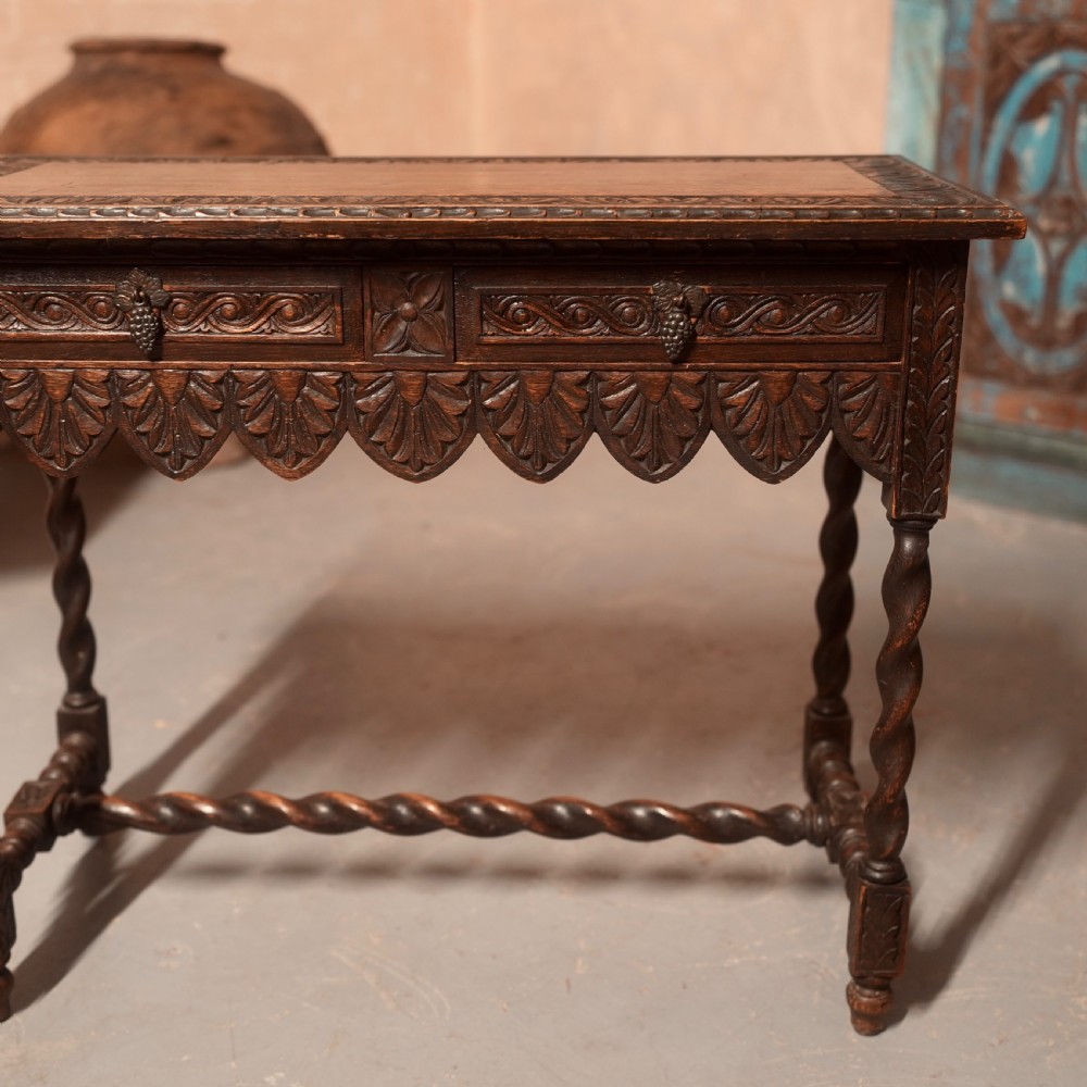 A 19th-century dark carved oak writing table featuring barley twist legs, a scalloped apron frieze, and twin drawers with ornate metal pulls. View III