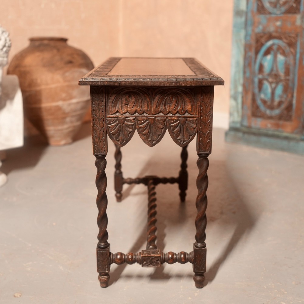 A 19th-century dark carved oak writing table featuring barley twist legs, a scalloped apron frieze, and twin drawers with ornate metal pulls. View VIII