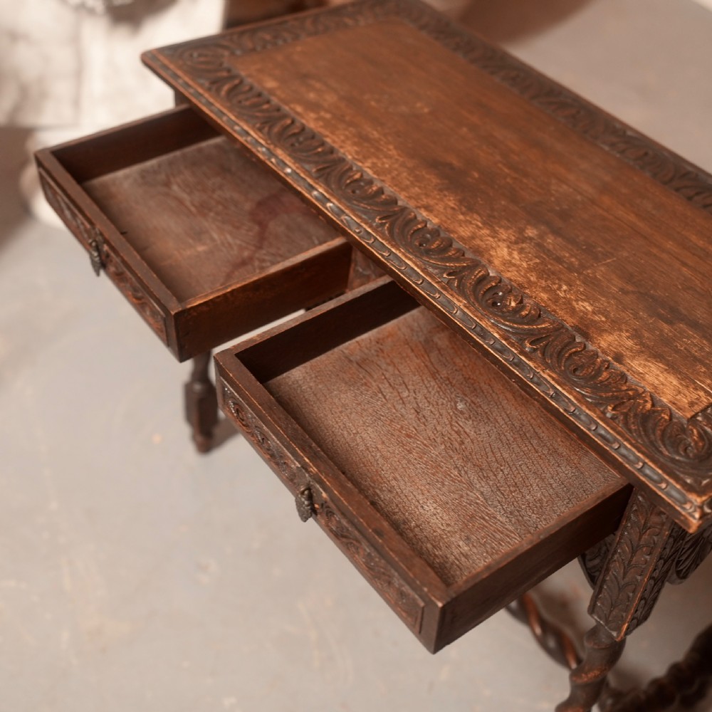 A 19th-century dark carved oak writing table featuring barley twist legs, a scalloped apron frieze, and twin drawers with ornate metal pulls. View IX