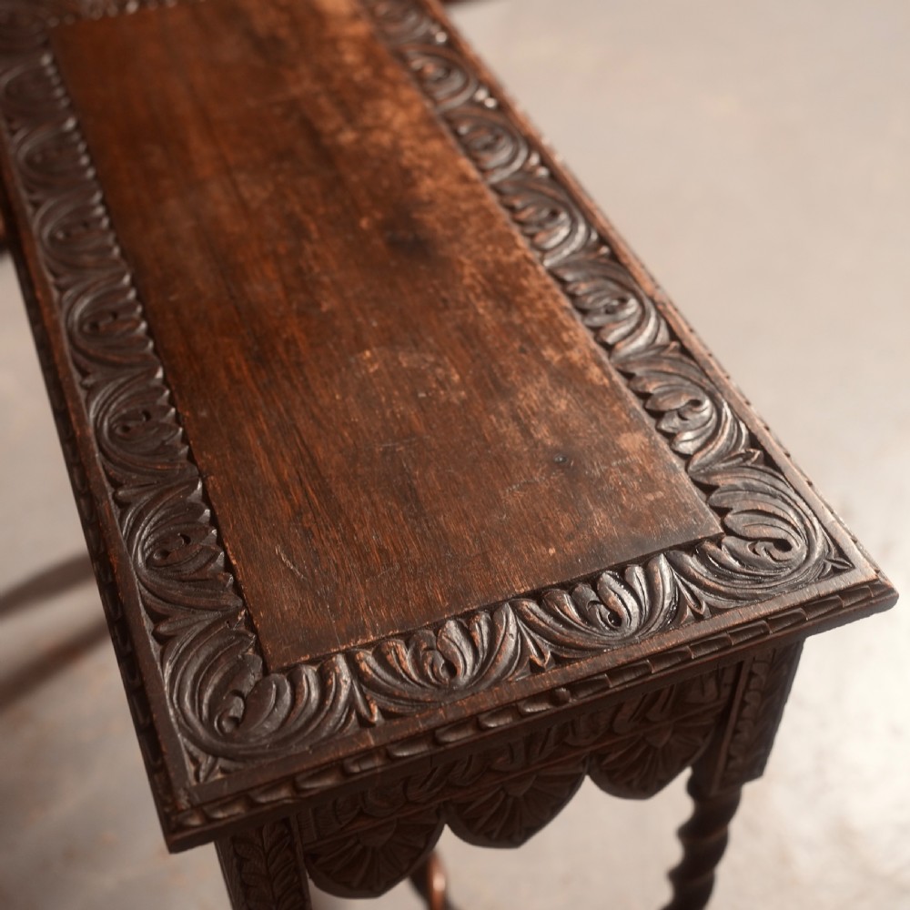 A 19th-century dark carved oak writing table featuring barley twist legs, a scalloped apron frieze, and twin drawers with ornate metal pulls. View XI