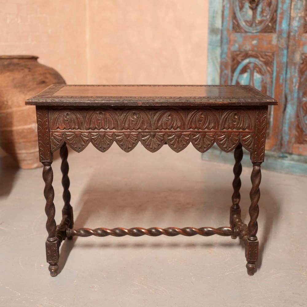 A 19th-century dark carved oak writing table featuring barley twist legs, a scalloped apron frieze, and twin drawers with ornate metal pulls. View XII