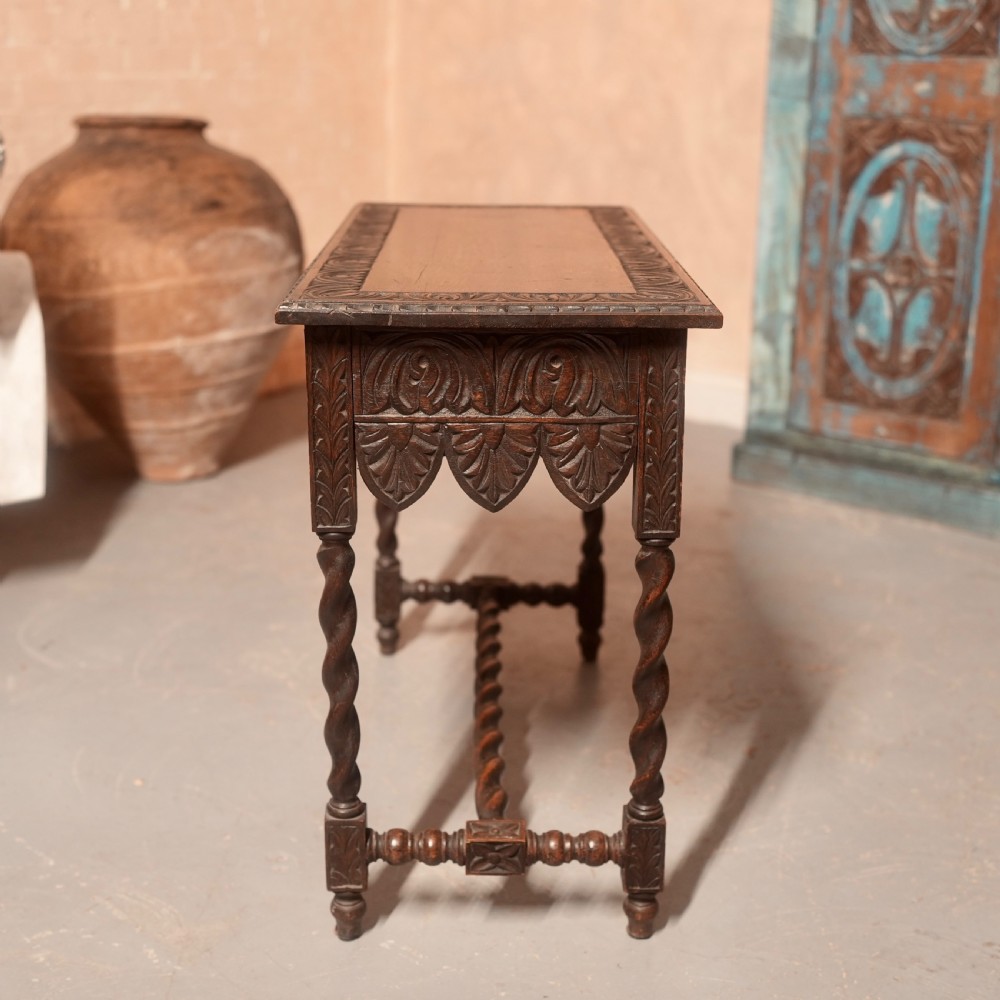 A 19th-century dark carved oak writing table featuring barley twist legs, a scalloped apron frieze, and twin drawers with ornate metal pulls. View XIII
