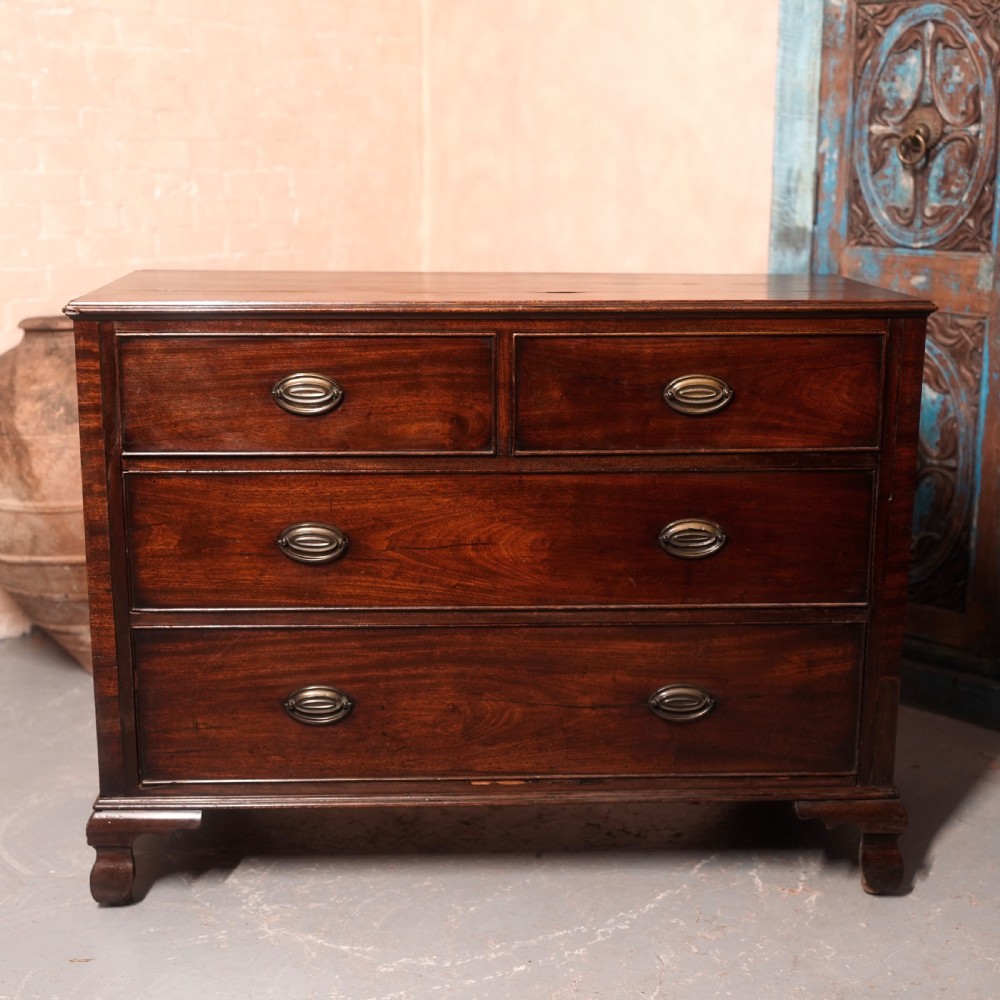 An 18th-century Georgian mahogany chest of drawers featuring two short over two long drawers, oval brass handles, and bracket feet.