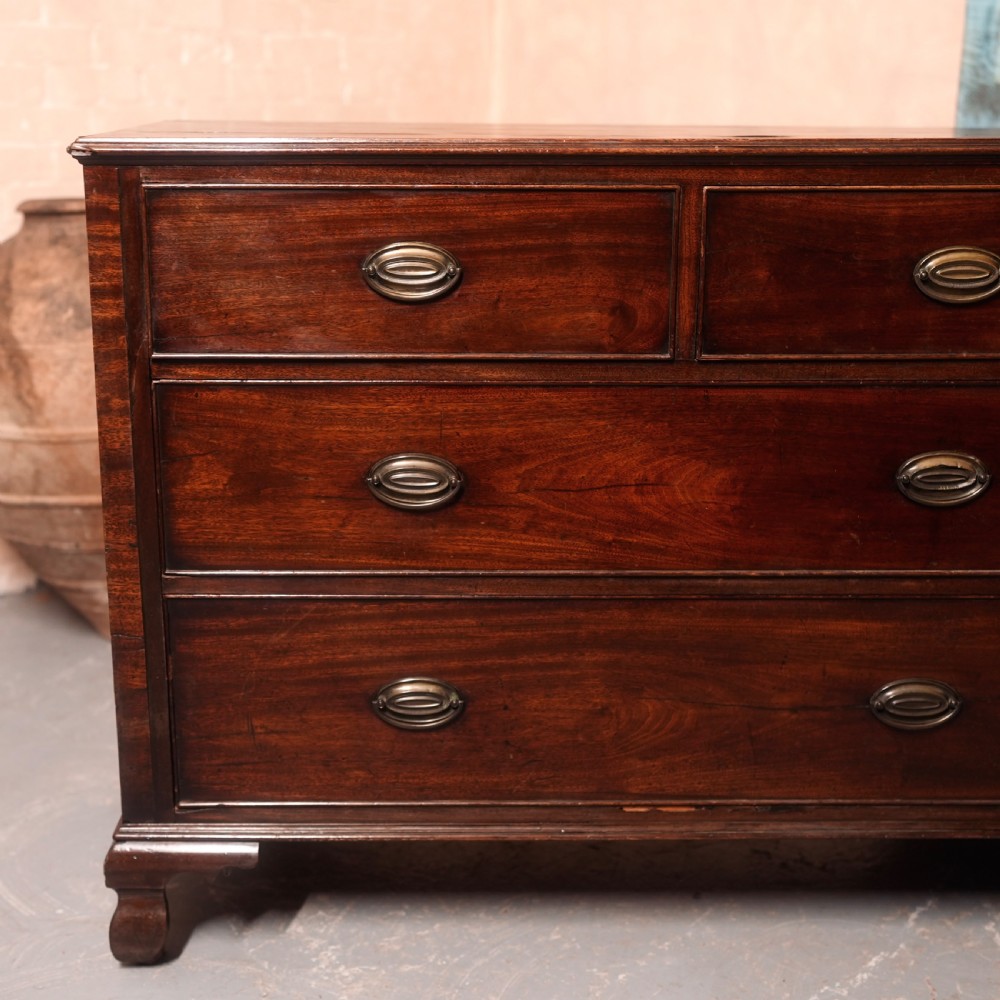 An 18th-century Georgian mahogany chest of drawers featuring two short over two long drawers, oval brass handles, and bracket feet. View II
