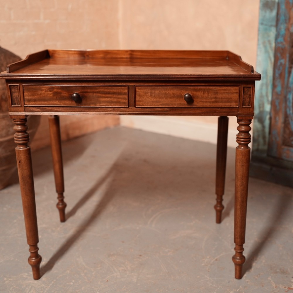 A Georgian mahogany writing table featuring a low gallery rim, two frieze drawers with turned wooden knobs, and slender turned legs. View II