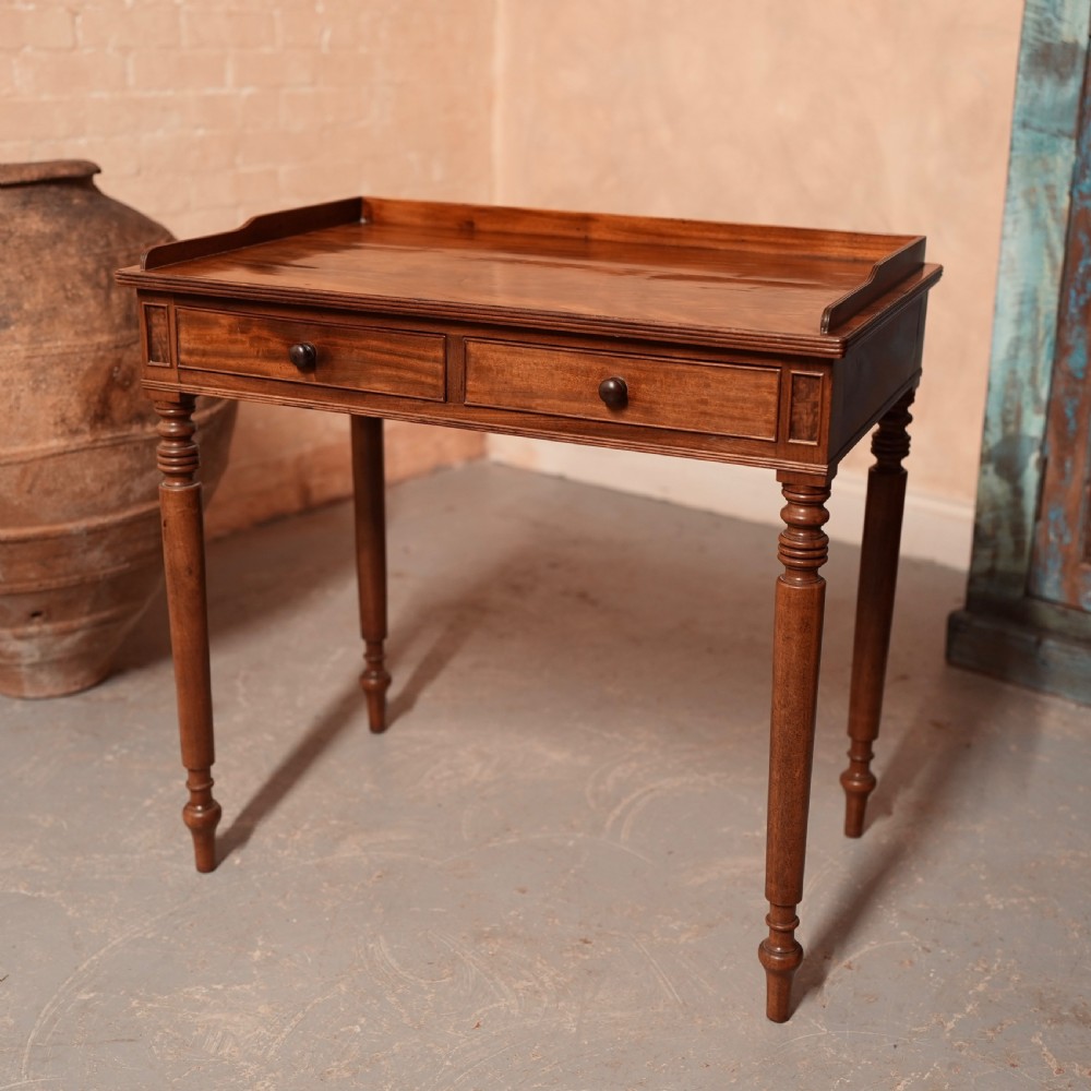 A Georgian mahogany writing table featuring a low gallery rim, two frieze drawers with turned wooden knobs, and slender turned legs. View IV