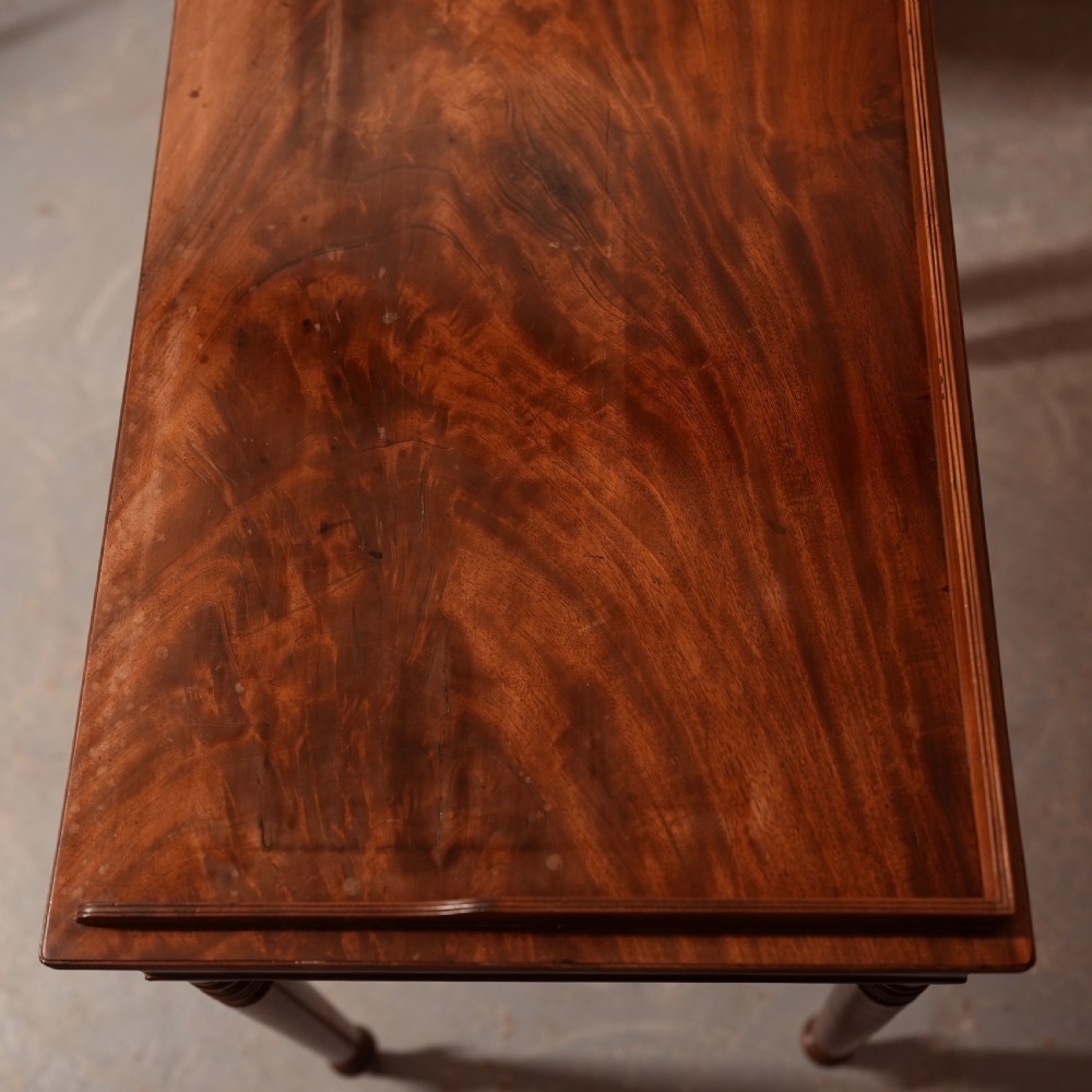A Georgian mahogany writing table featuring a low gallery rim, two frieze drawers with turned wooden knobs, and slender turned legs. View VI