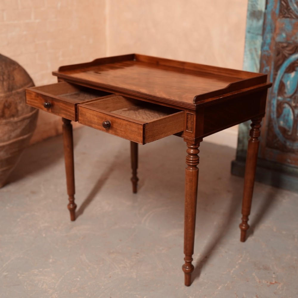 A Georgian mahogany writing table featuring a low gallery rim, two frieze drawers with turned wooden knobs, and slender turned legs. View VIII