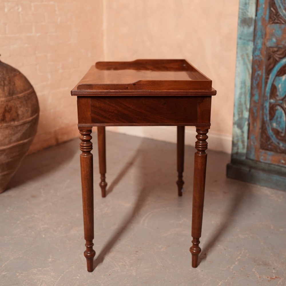 A Georgian mahogany writing table featuring a low gallery rim, two frieze drawers with turned wooden knobs, and slender turned legs. View XI