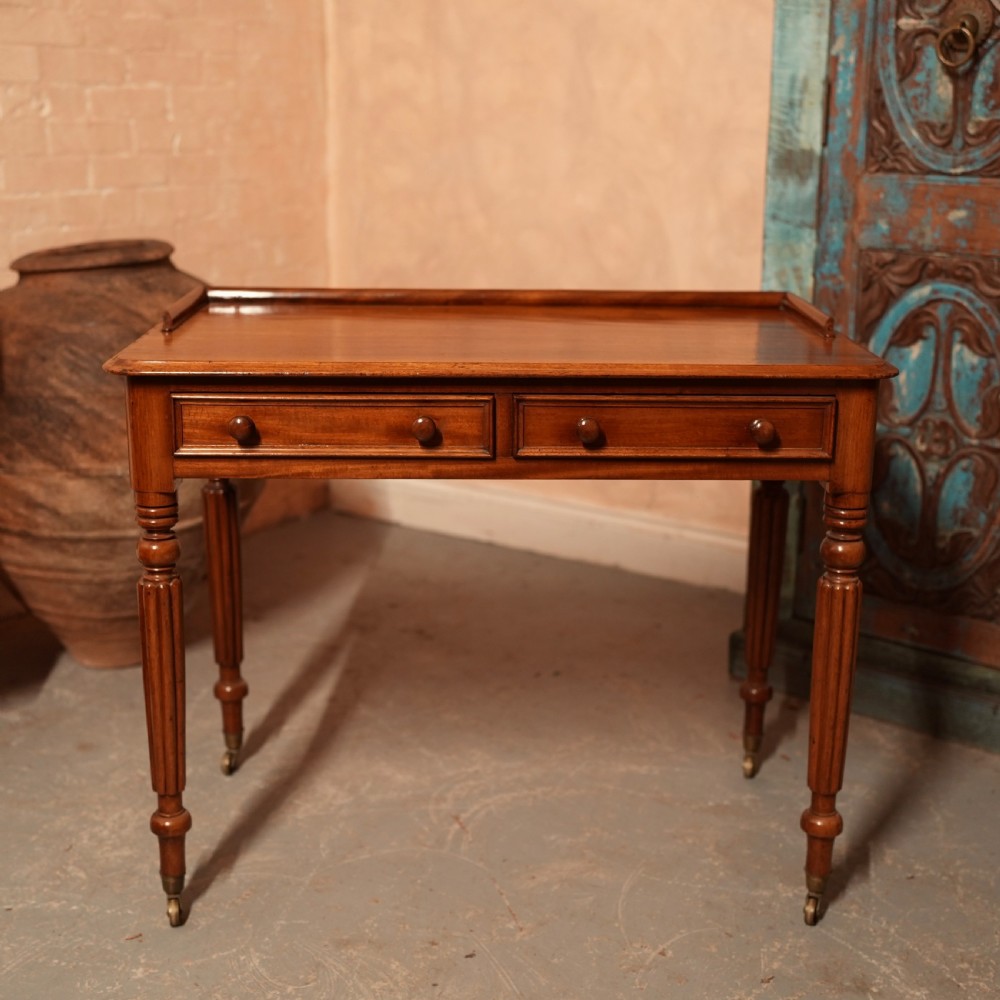 A William IV mahogany writing table featuring a raised gallery top, two frieze drawers with wooden knob handles, and reeded turned legs with brass castors. View III