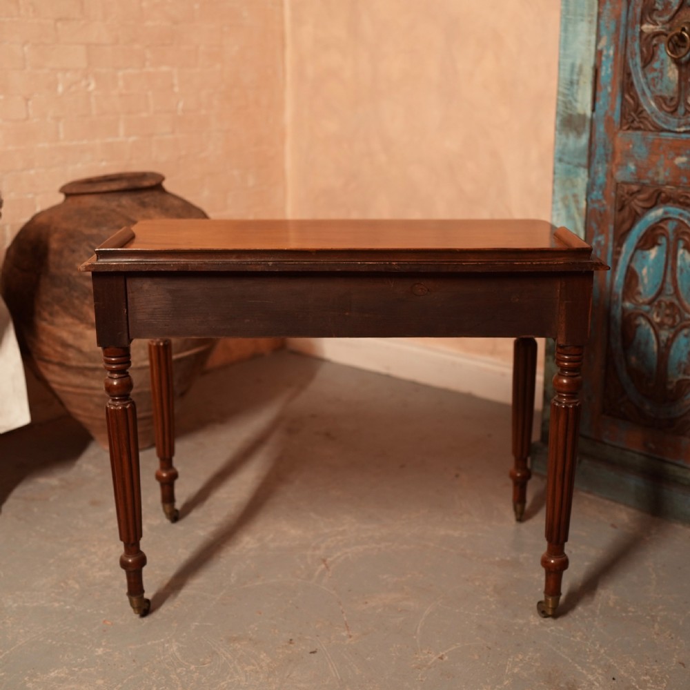 A William IV mahogany writing table featuring a raised gallery top, two frieze drawers with wooden knob handles, and reeded turned legs with brass castors. View XIII